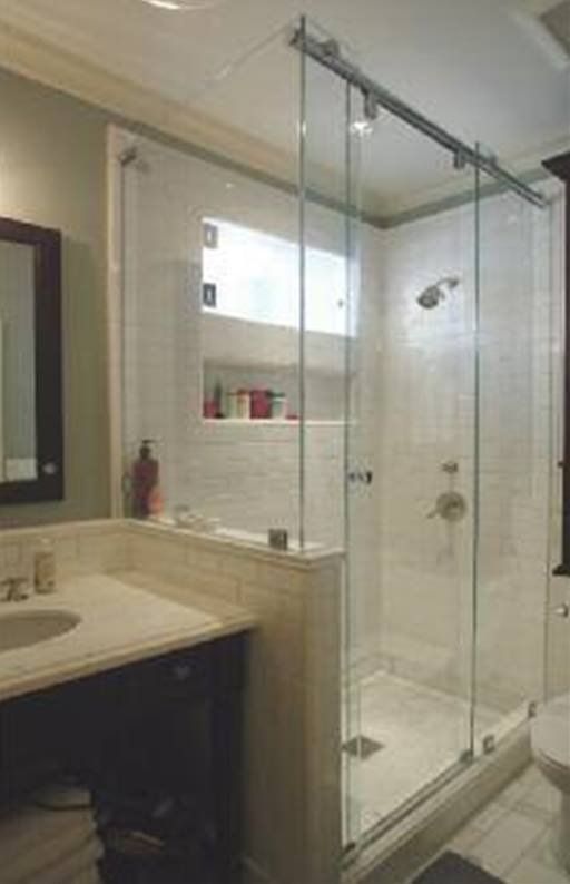 Glass shower enclosure in a bathroom, with a sliding door and white tile.