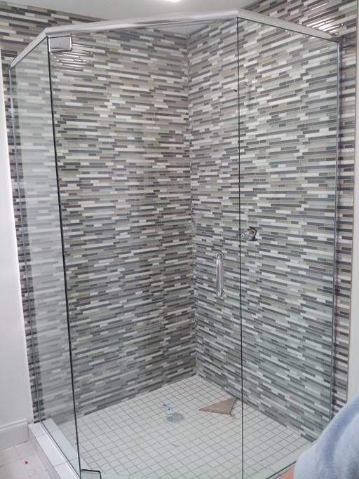 Glass-enclosed shower with gray and white tiled walls and floor.