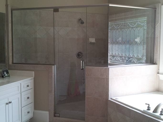 A modern bathroom with a glass shower enclosure next to a bathtub and vanity.