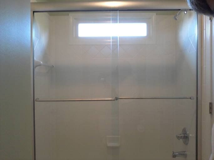 Glass shower door in bathroom with a small window above the shower head.