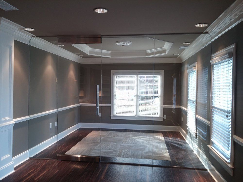 Empty room with dark wood floor, grey walls, white trim, recessed lighting, and large glass door.