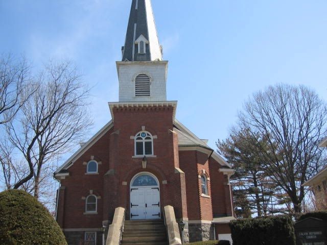 A brick church with a steeple and stairs leading up to it