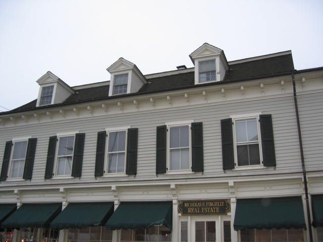 A large white building with black shutters and green awnings
