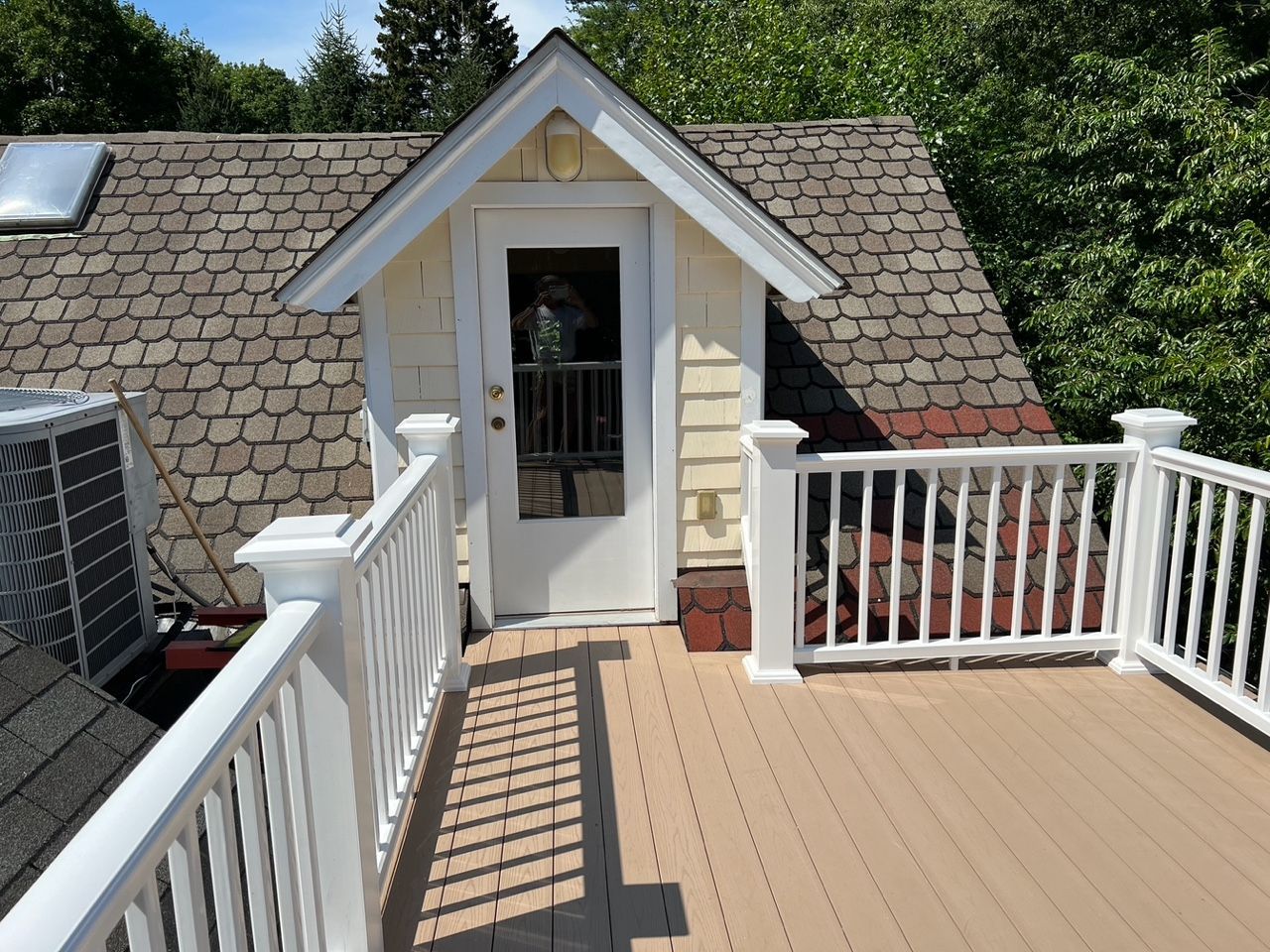 A rooftop deck with a white railing and a door