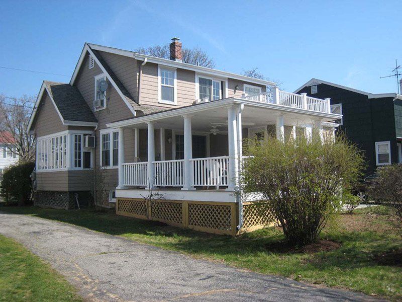 A house with a large porch and a driveway leading to it