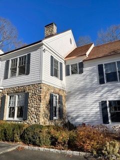 A large white house with black shutters and a stone chimney