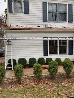 A white house with blue shutters and a ladder on the side of it