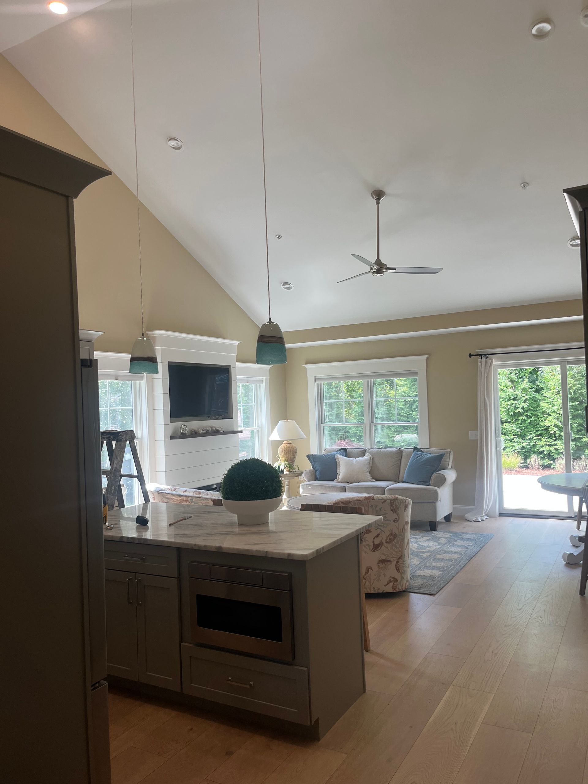 Open-concept living space with kitchen island, fireplace, and sliding glass door to a patio.