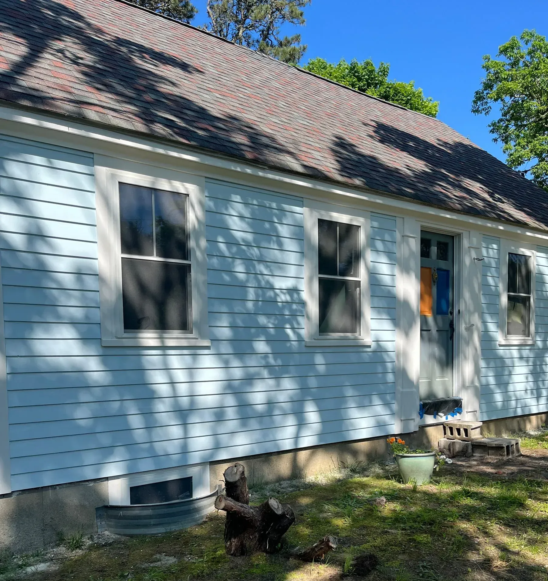 Light blue house with white trim, three windows, and a brown roof.