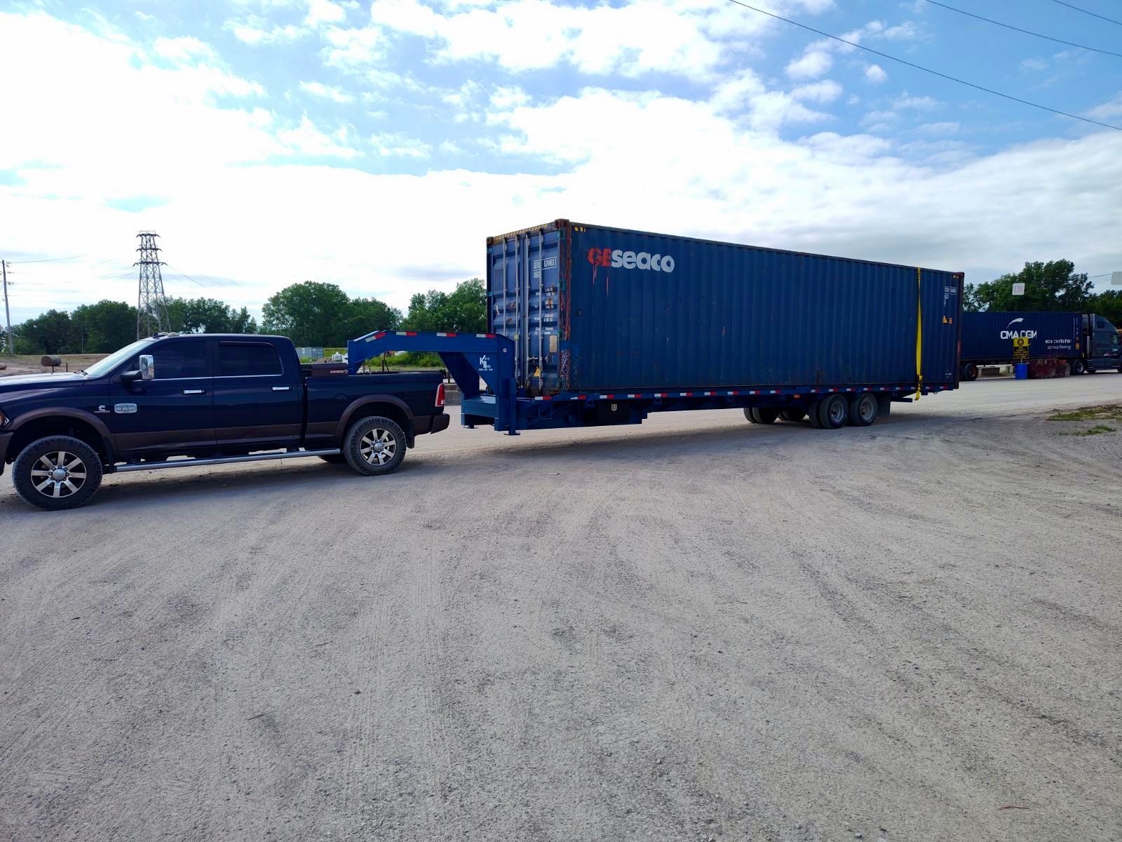 A truck is pulling a large blue shipping container