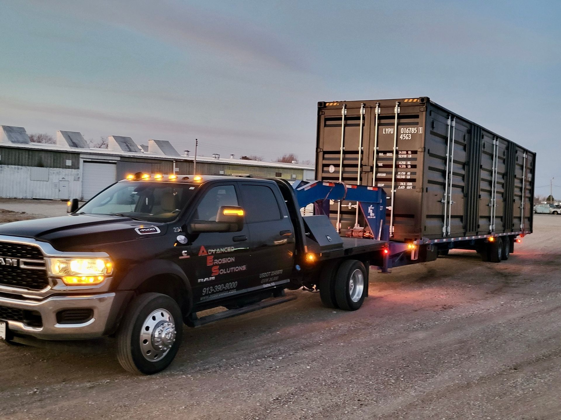 A Ram truck is towing a large container on a trailer