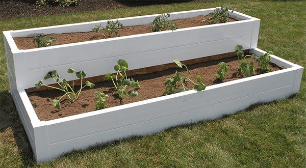 A white planter filled with plants is sitting on top of a lush green lawn.