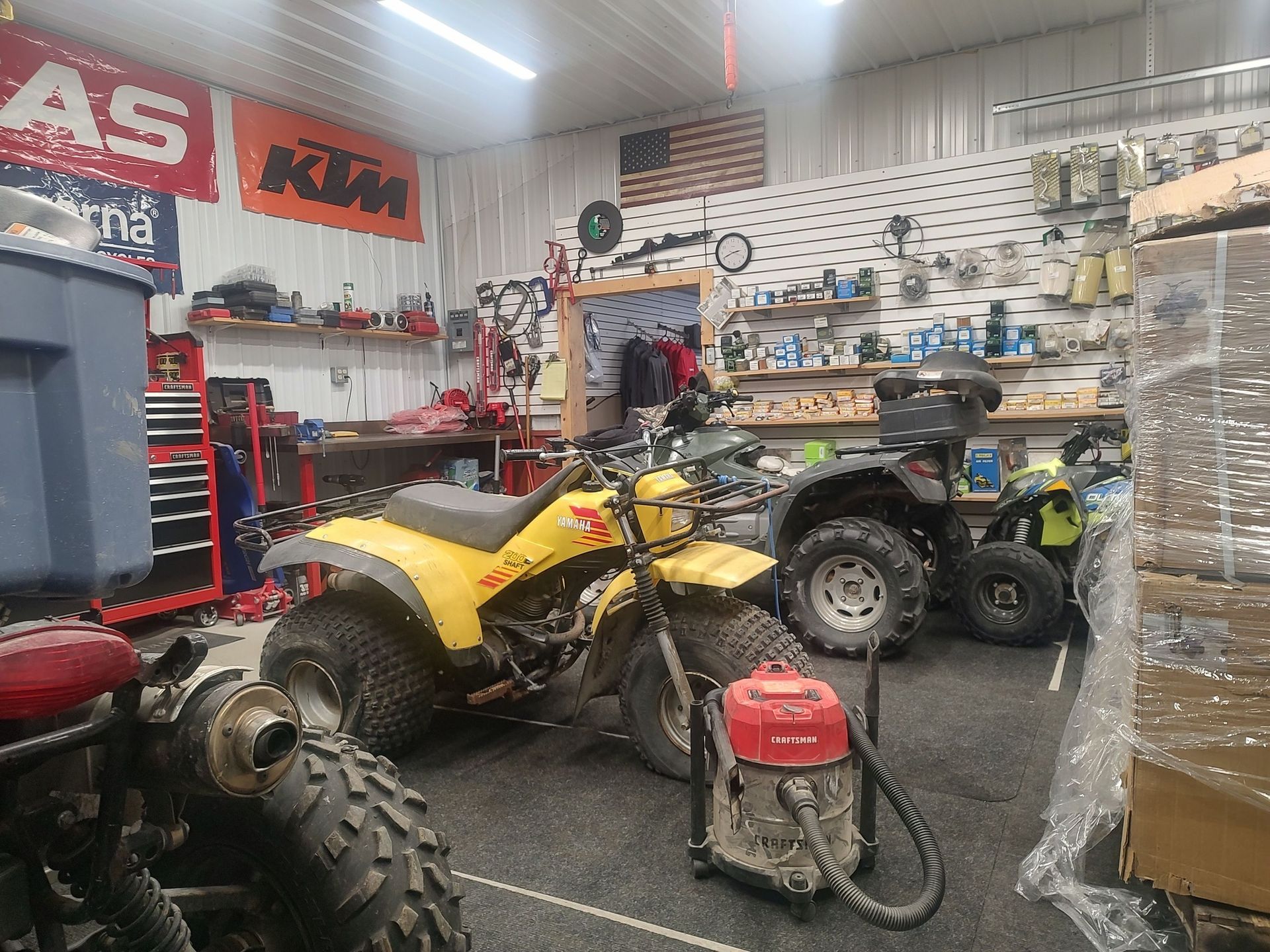 Yellow three-wheeled ATV and various tools and equipment in a garage.