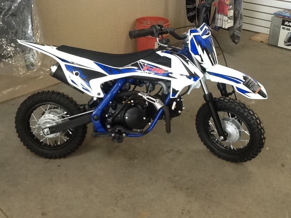 White and blue dirt bike in a shop setting.