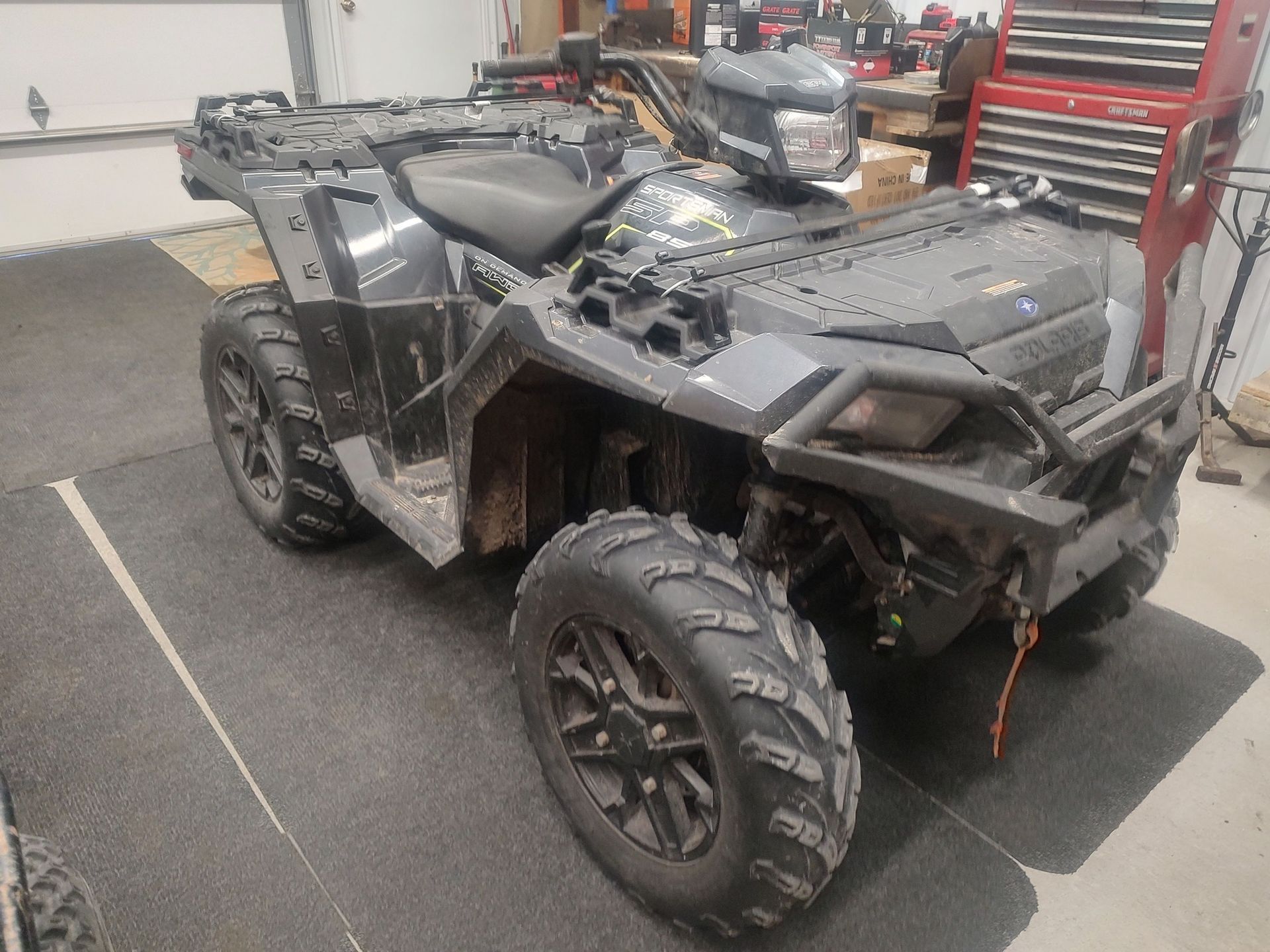Dark gray Polaris ATV parked on a garage floor.