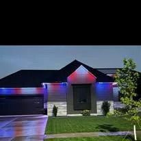 Suburban house at night with red and blue holiday lights glowing on the roof and garage.