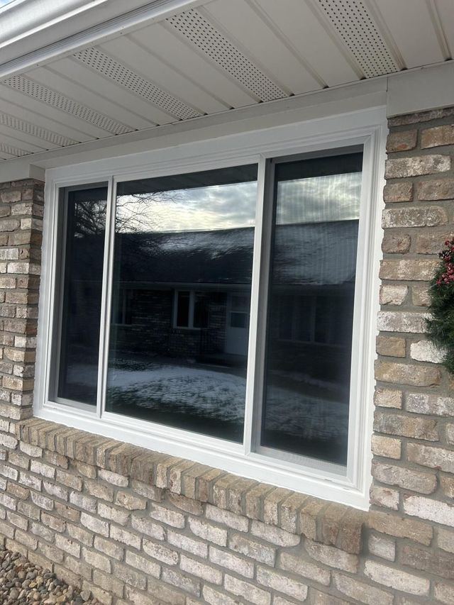 White sliding window set in a brick house exterior under a covered porch.
