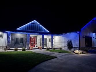 Blue-lit suburban house at night with lit porch, front lawn, and driveway