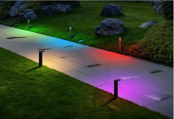 Colorful garden path lights illuminating a walkway at dusk, with red, blue, purple, and green glows on the pavement