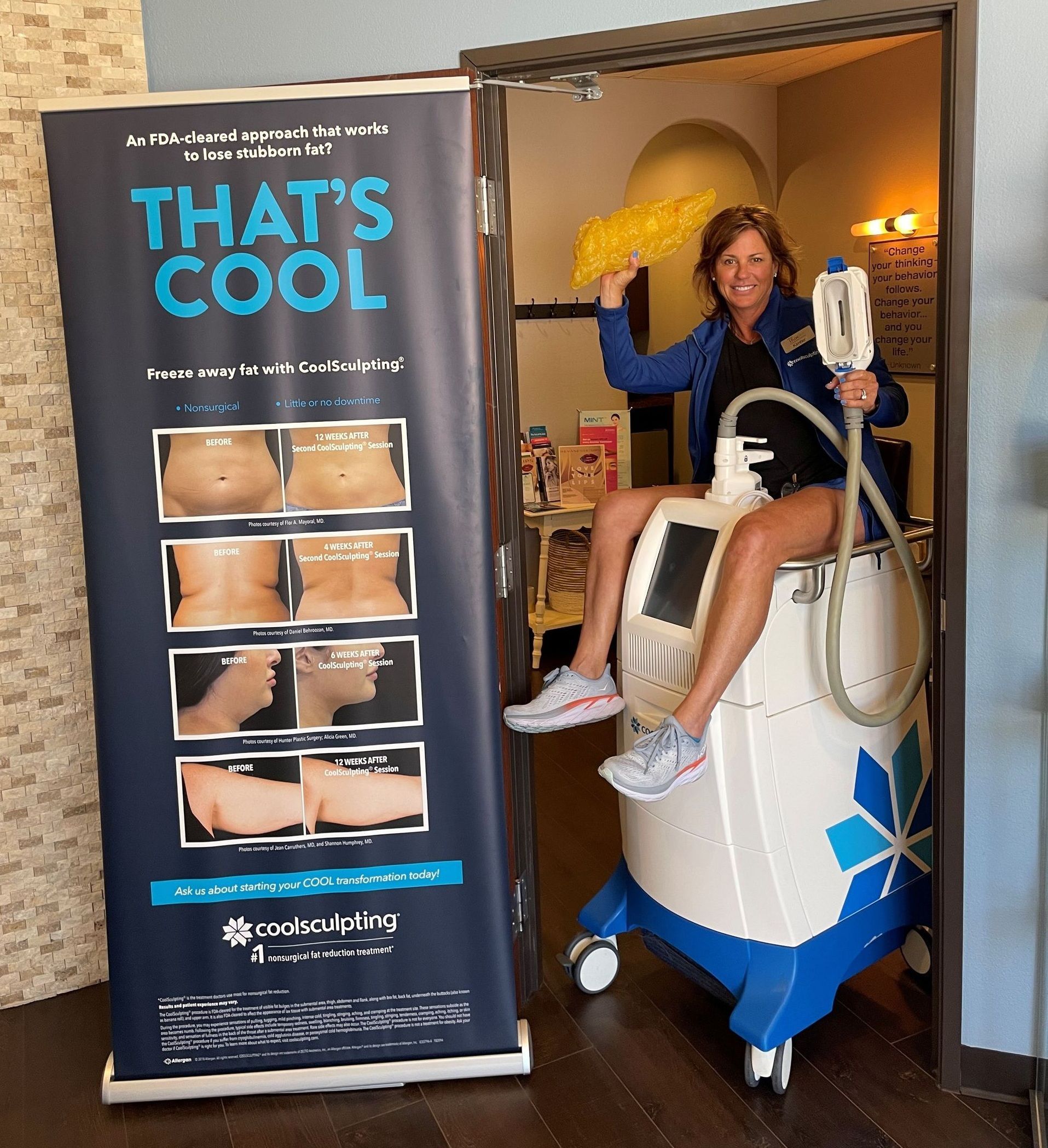 Woman on a body contouring machine by a That's Cool banner with before/after photos. Smiles, indoors.