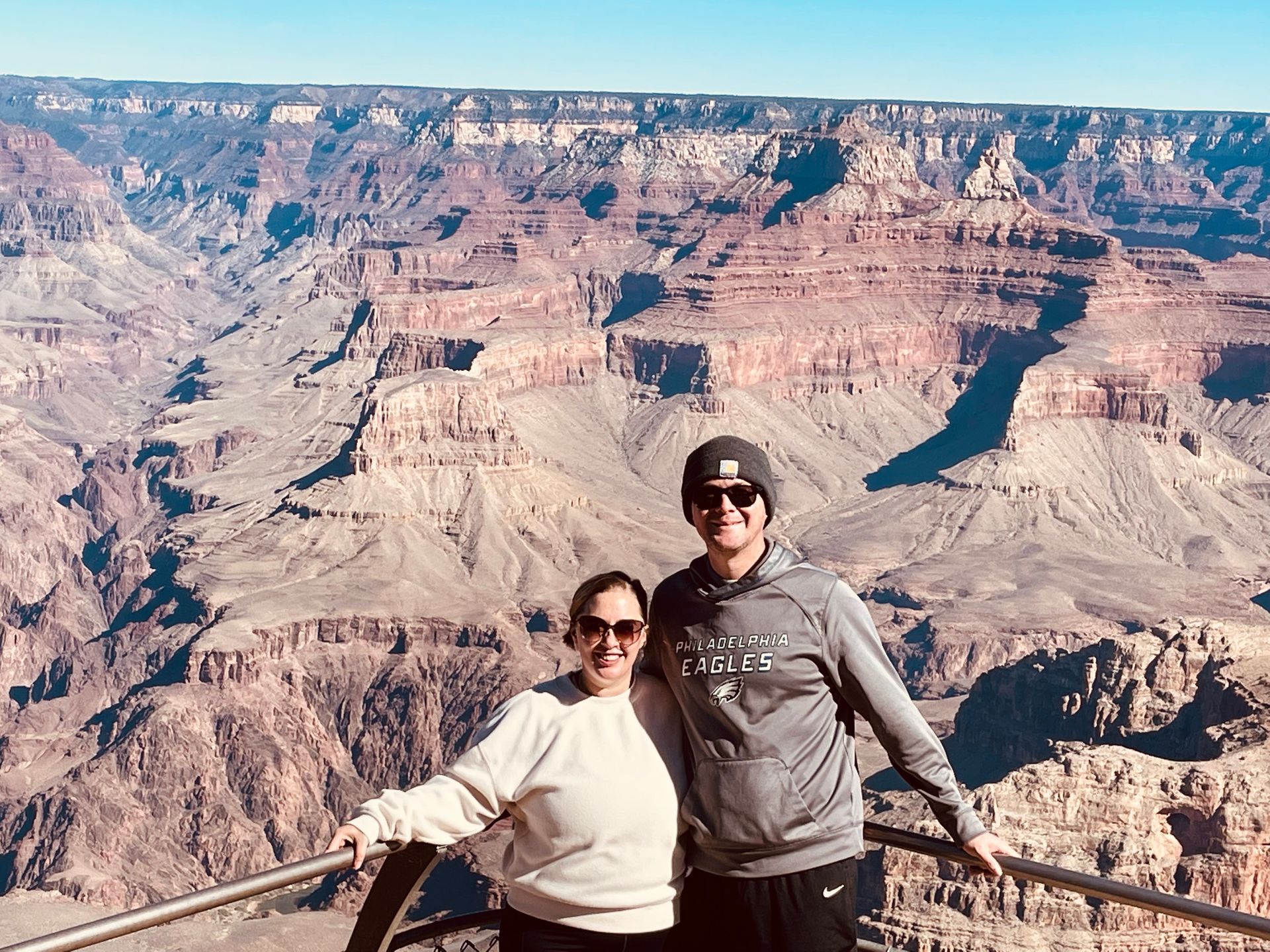 A man and a woman are posing for a picture at the grand canyon.