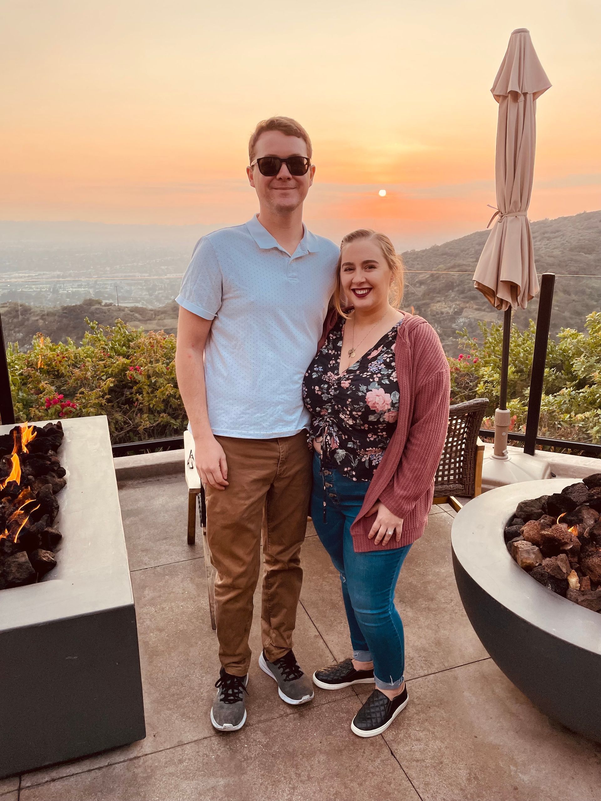 A man and a woman are posing for a picture in front of a fire pit.