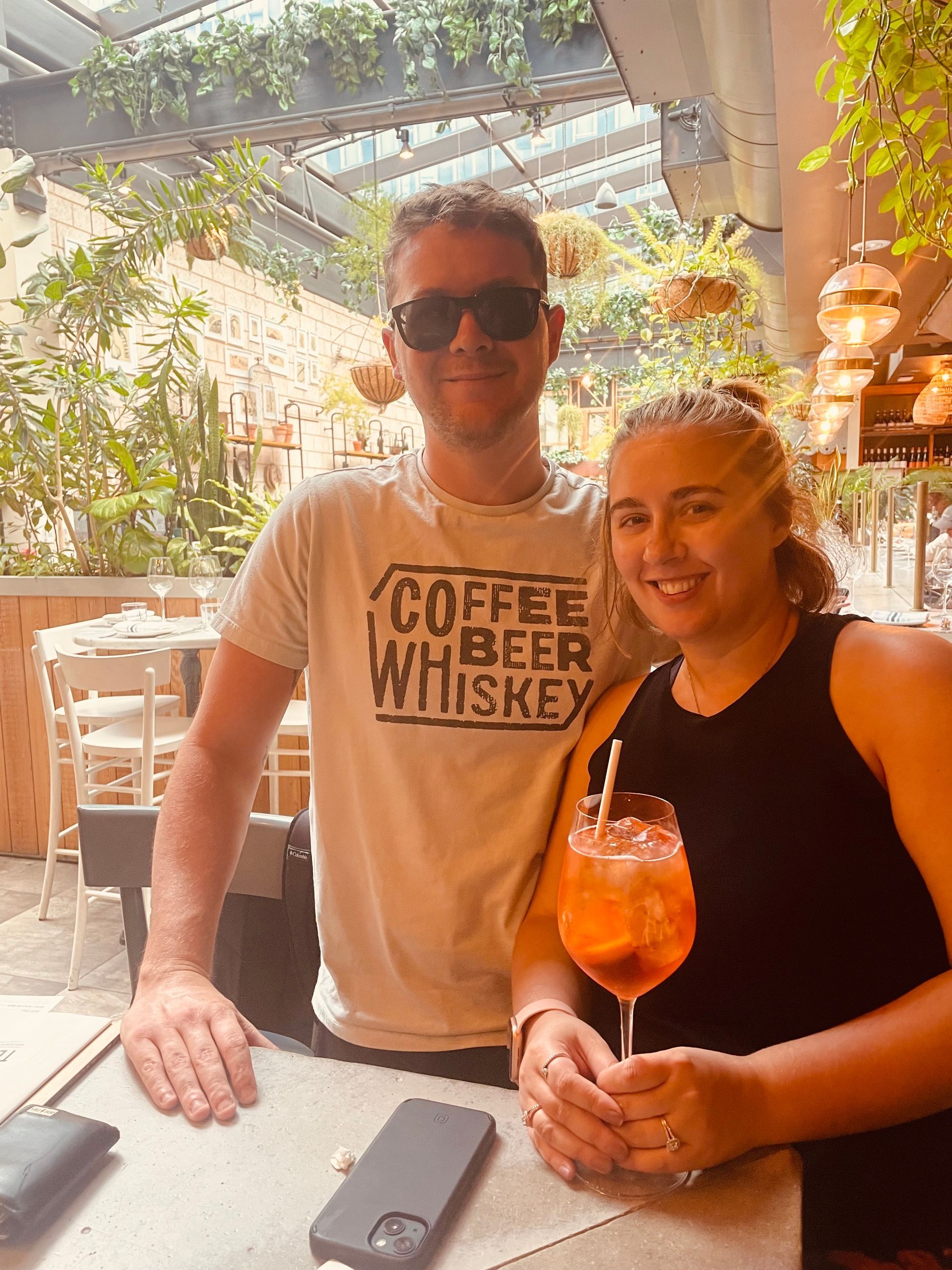 A man and a woman are sitting at a table holding a glass of wine.