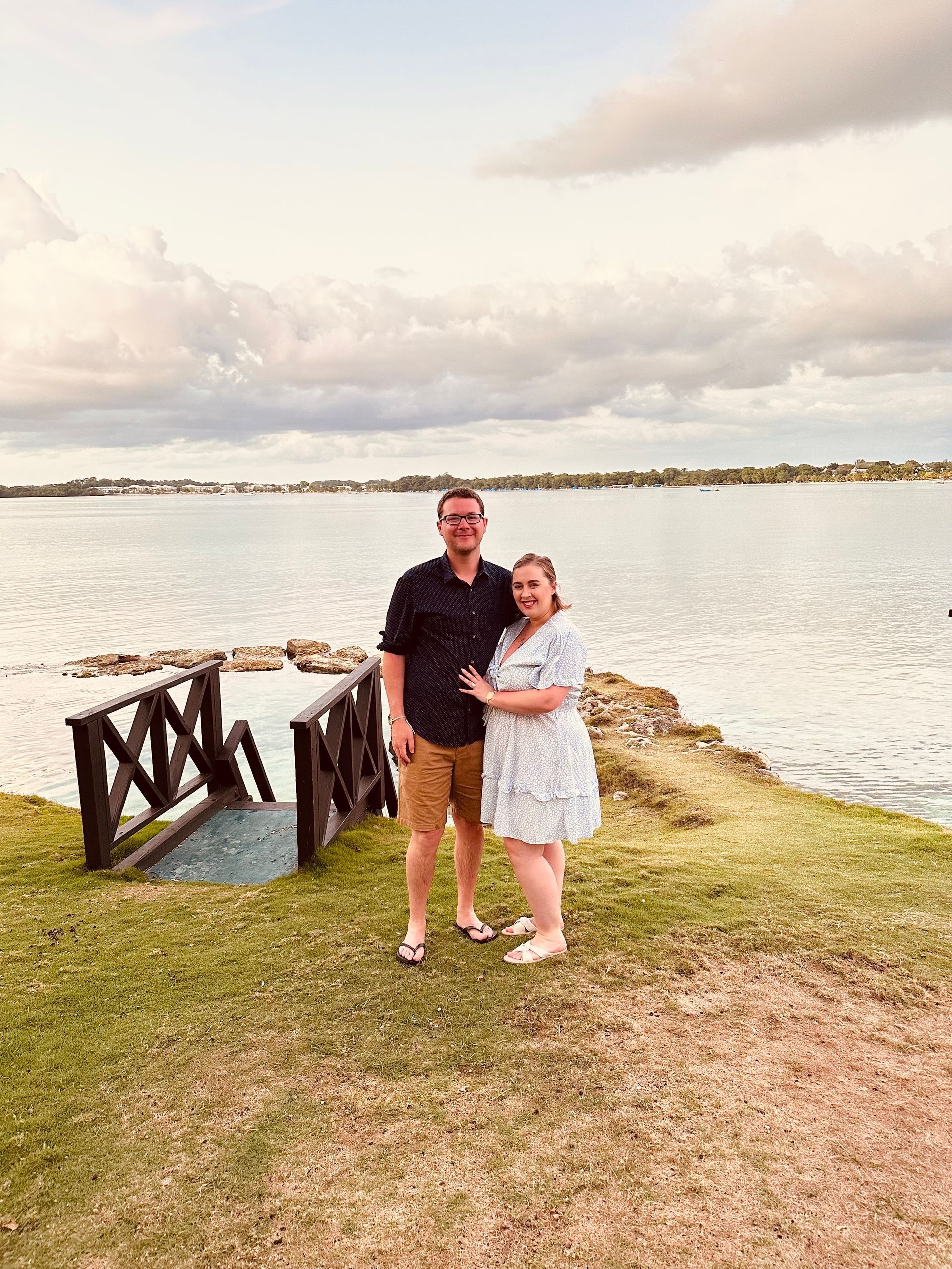 A man and a woman are standing in front of a body of water.
