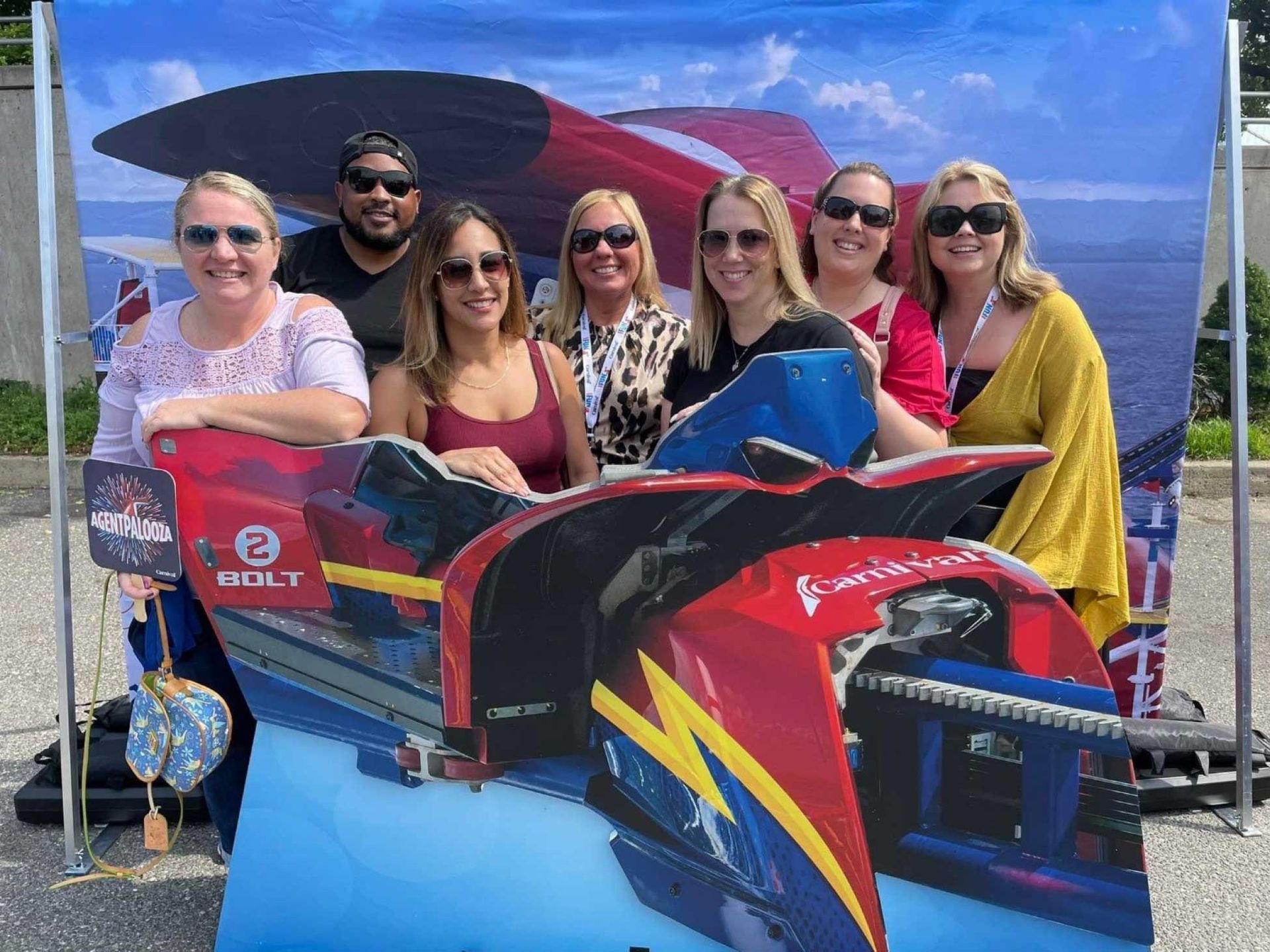 a group of people posing behind a cutout of a red and blue racing boat