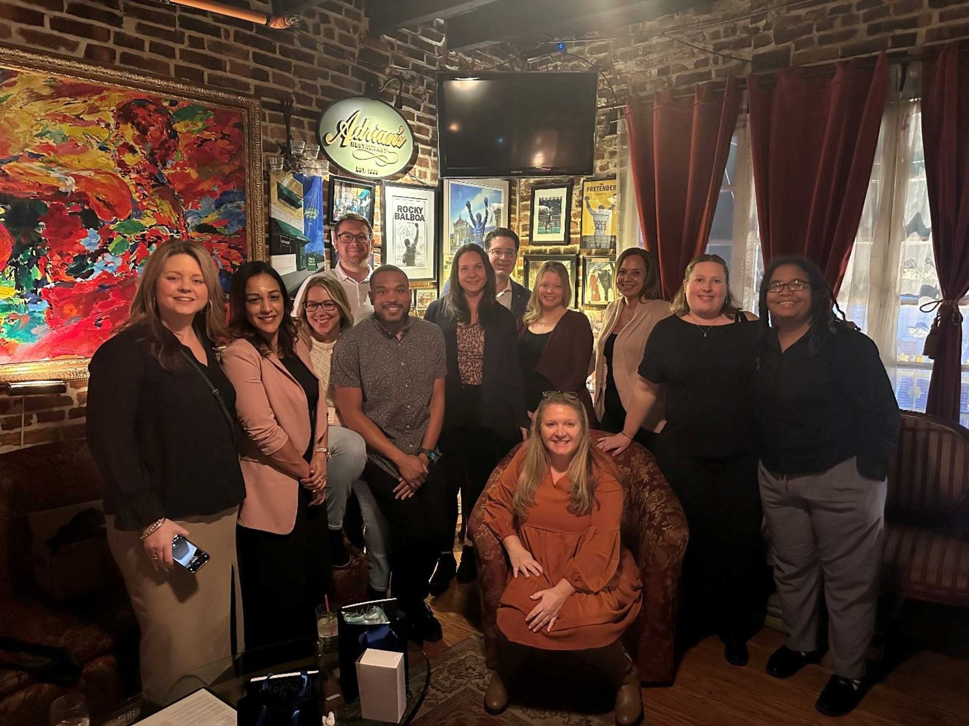 a group of people posing for a photo inside a dimly lit, art-filled bar