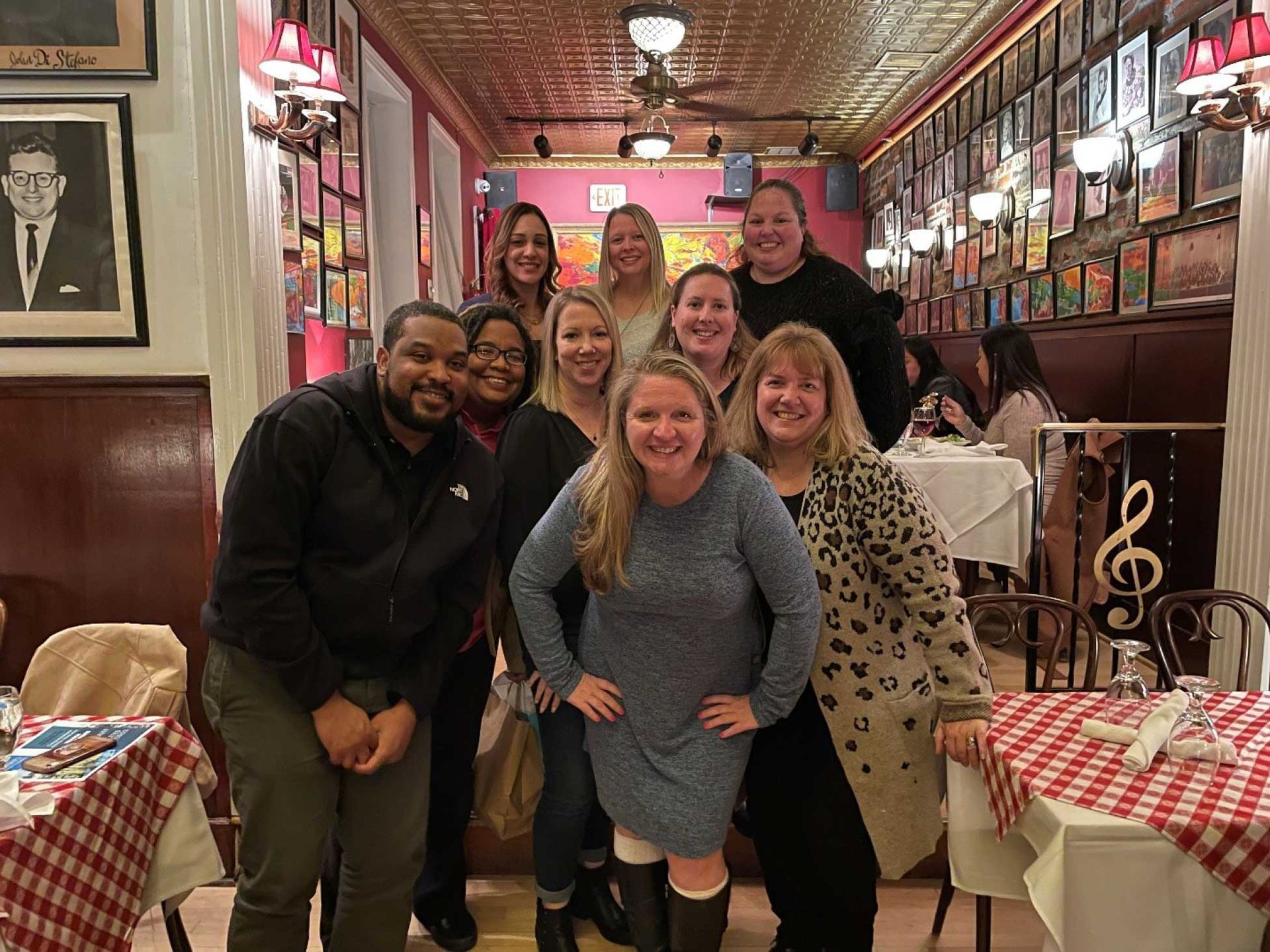 a group of people posing at a restaurant with red and white checkered tablecloths