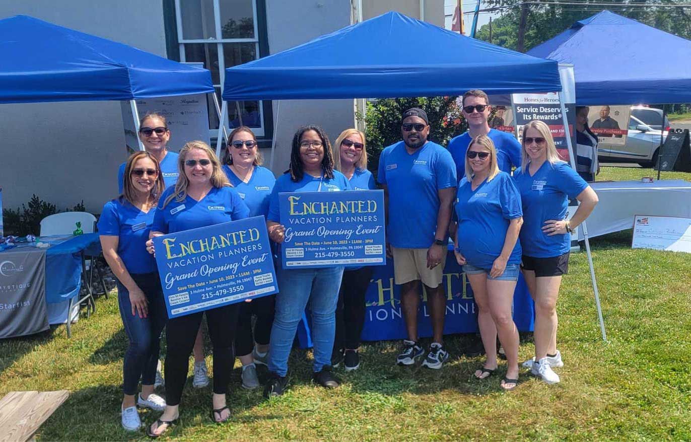 a group of people in blue shirts and tents pose with signs at an outdoor event