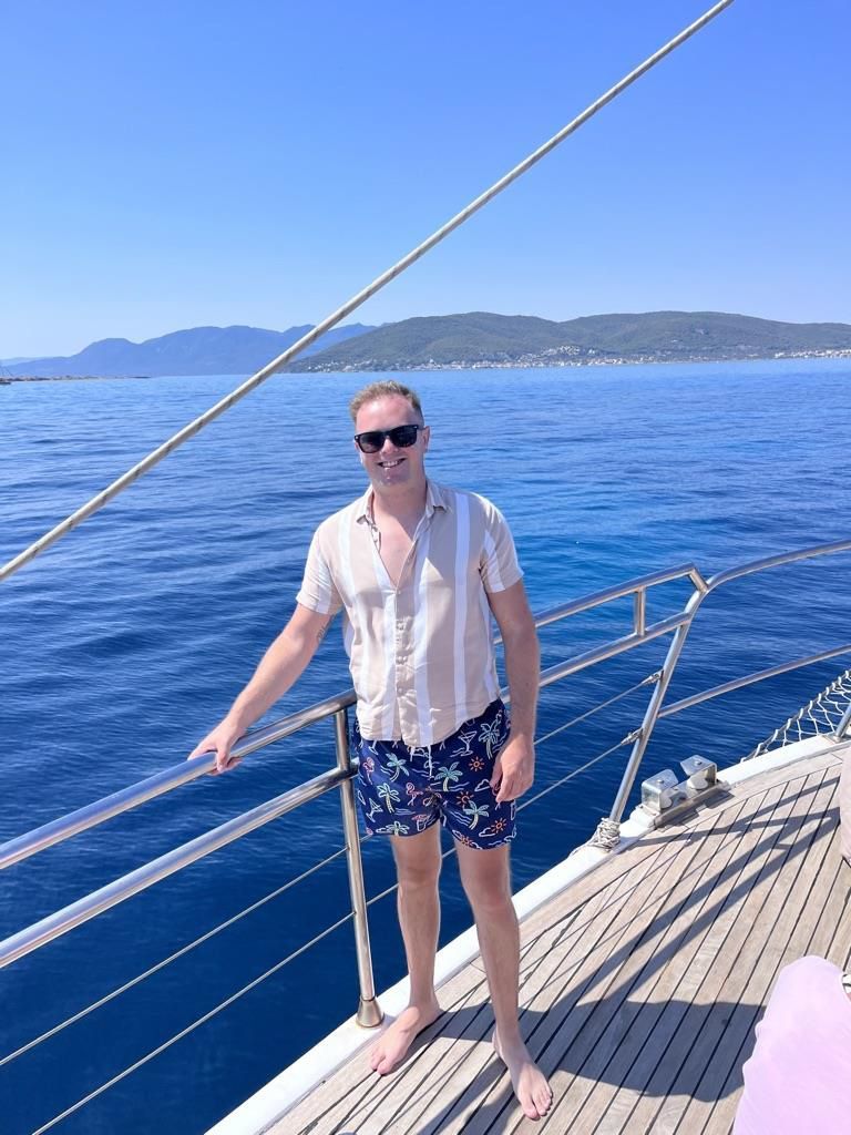 A man is standing on the deck of a boat in the ocean.