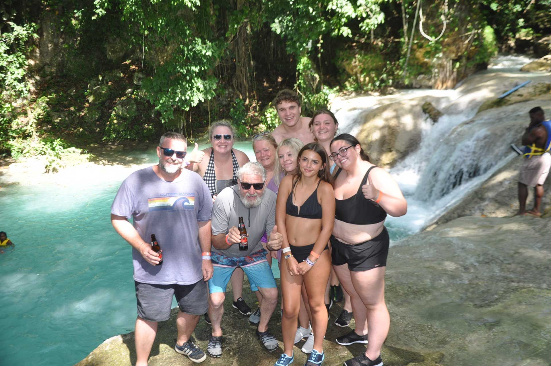 a group of people posing near a turquoise waterfall