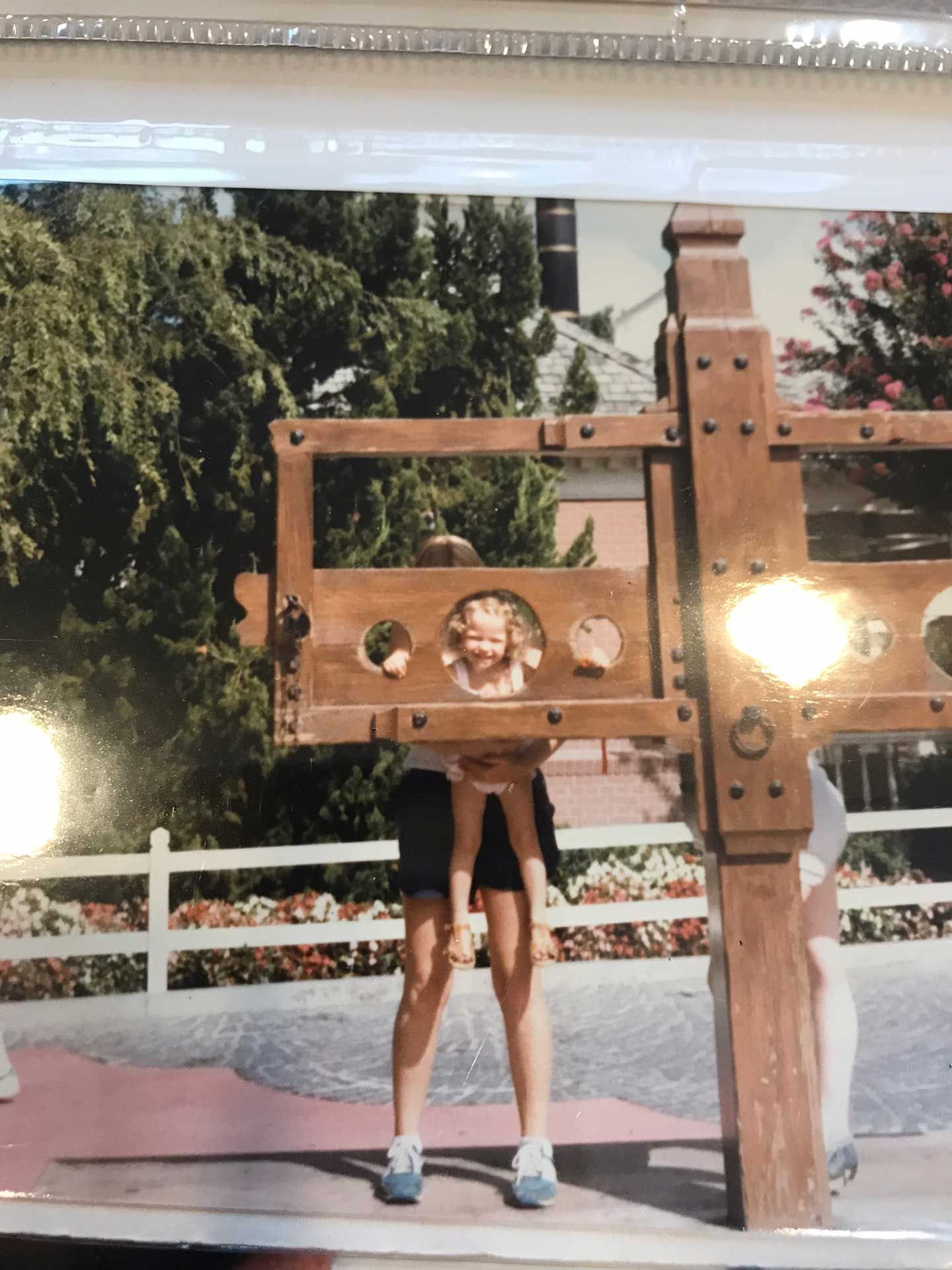 a girl in stocks held up by an adult
