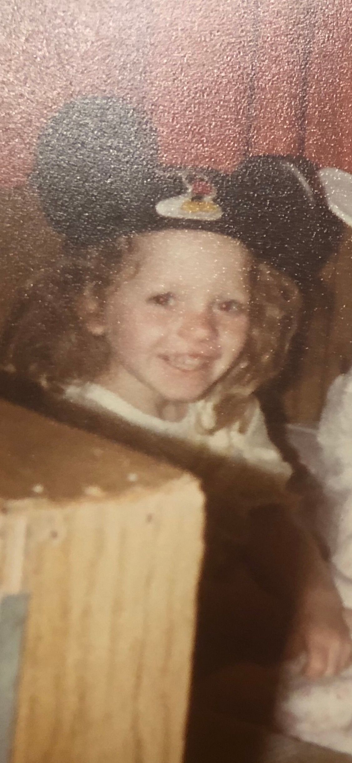 a young girl with curly blonde hair wearing Mickey Mouse ears
