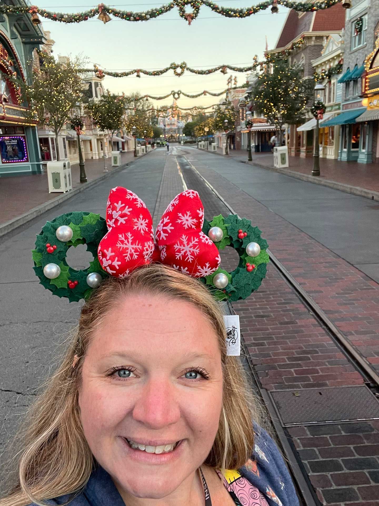 a woman in Christmas Minnie ears smiles in Disneyland, Main Street