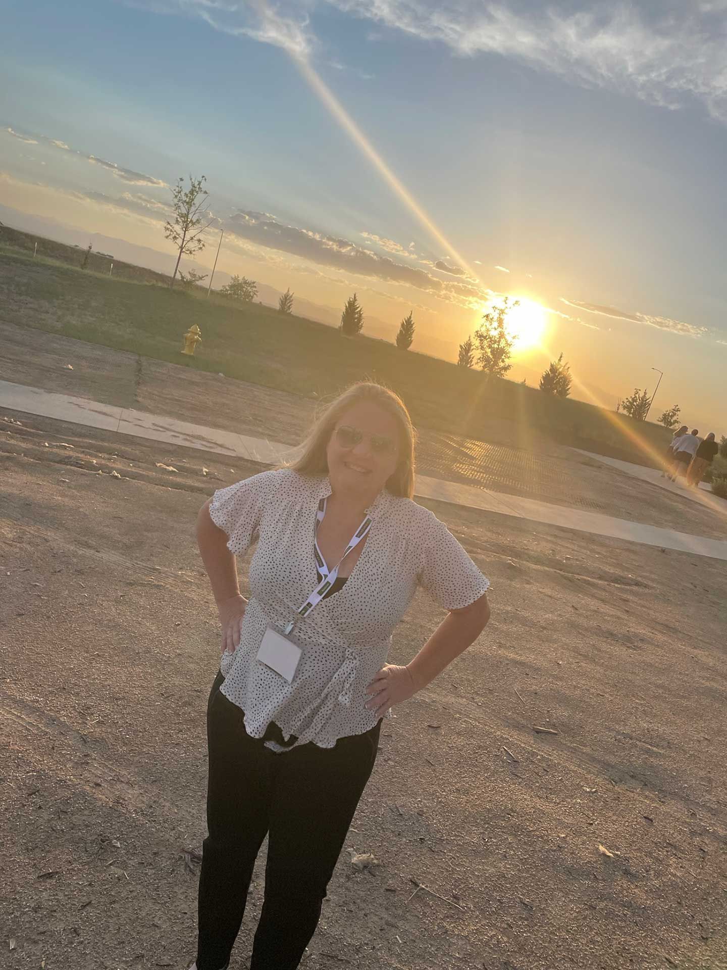 a woman standing outdoors at sunset, hands on hips