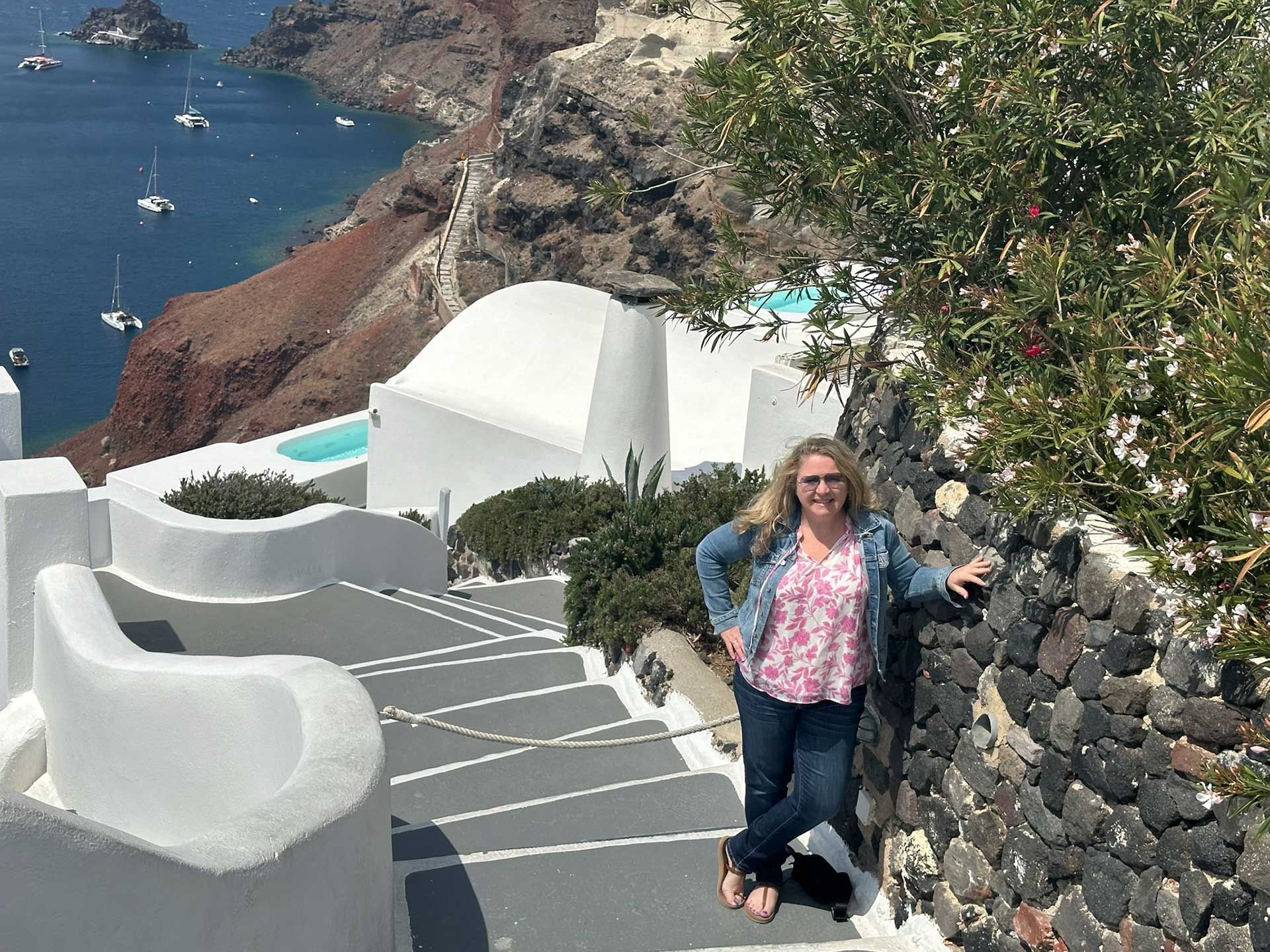 a woman posing on steps in Greece, overlooking the sea