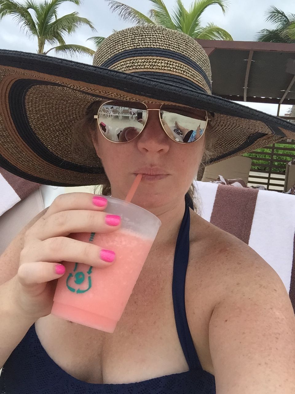 a woman wearing a hat sipping a drink outdoors