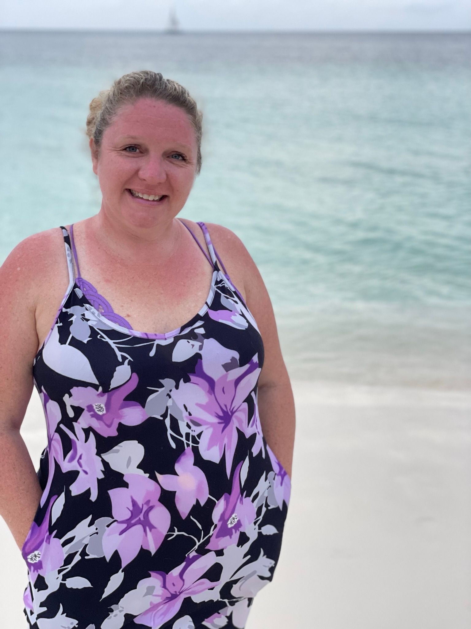 a woman in a floral dress standing on a beach