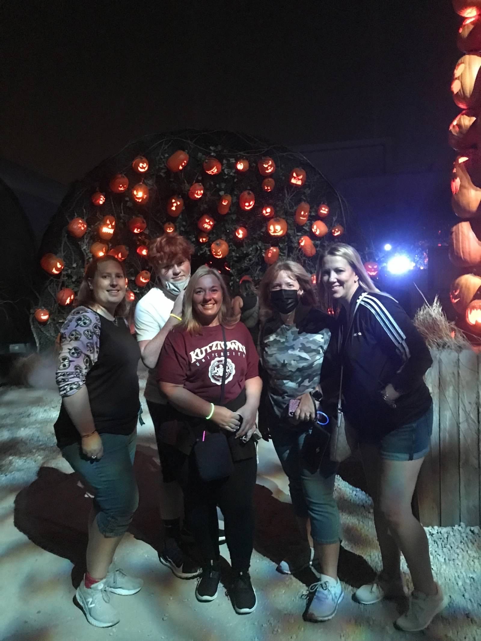 A group of women are posing for a picture in front of a pumpkin tree