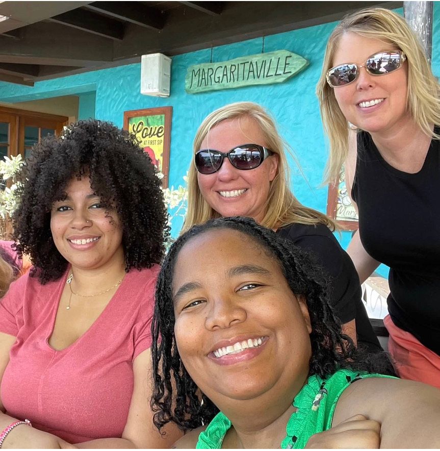 A group of women are posing for a picture in front of a sign