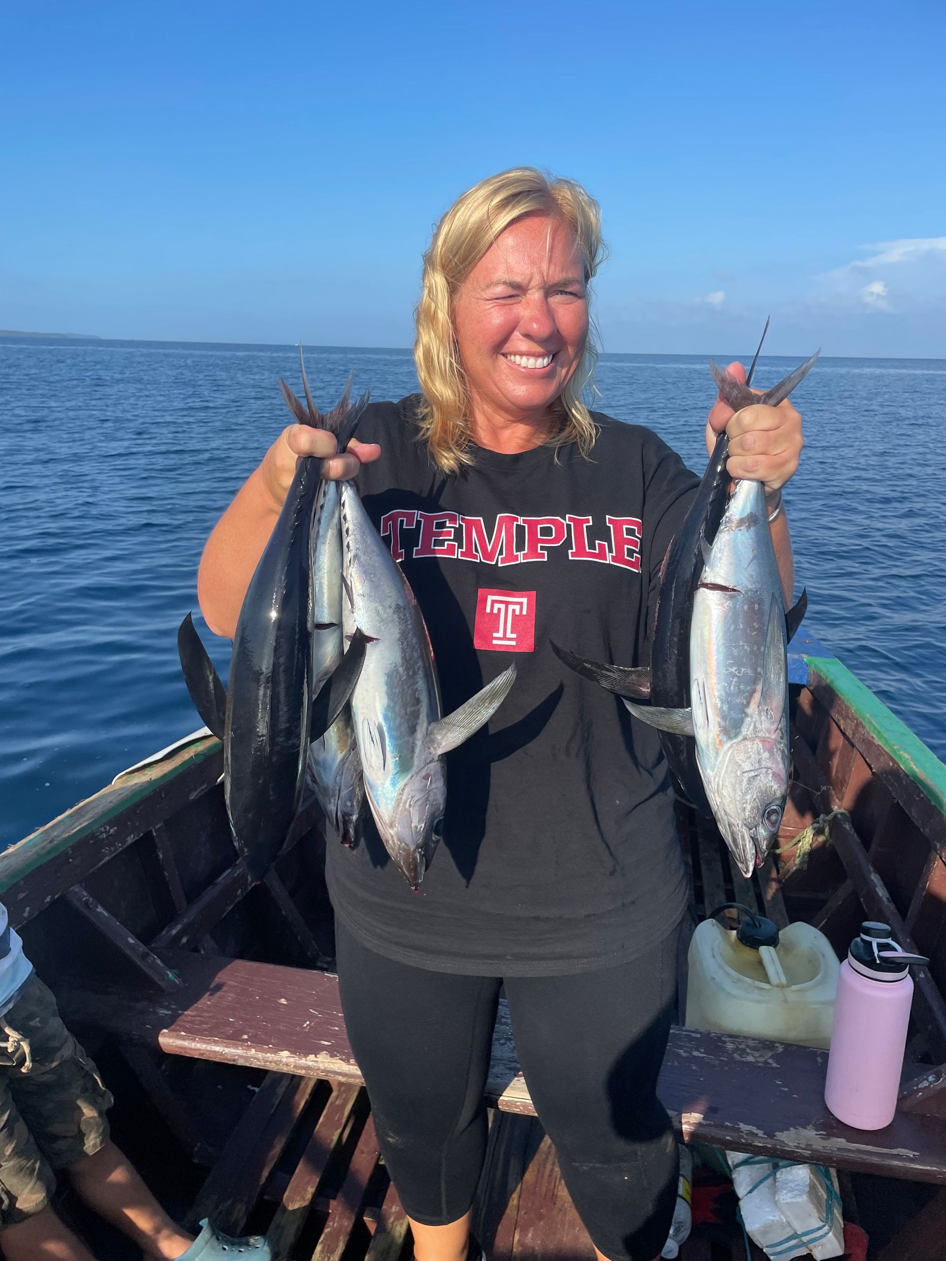 A woman in a black shirt is holding two fish