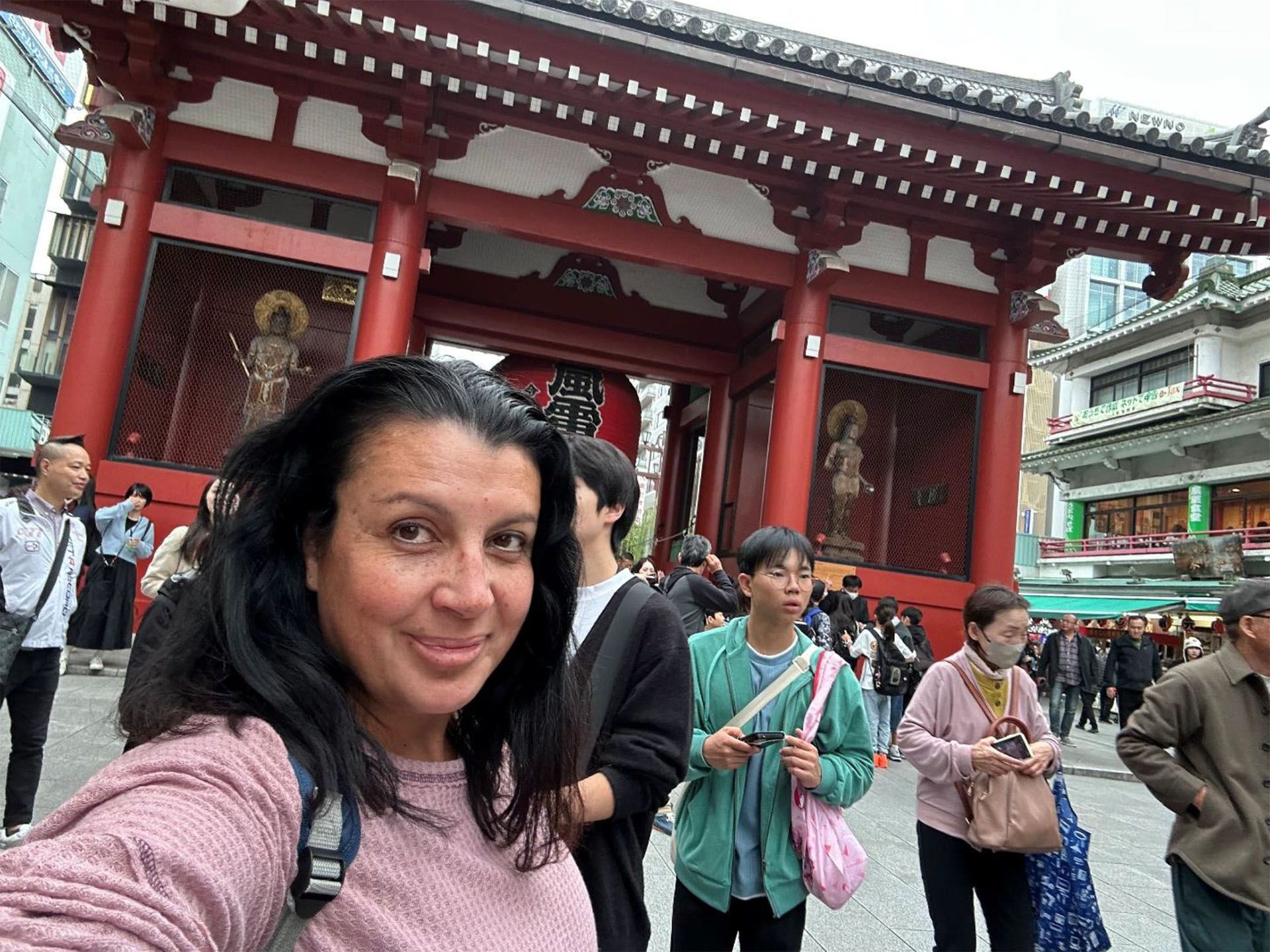 Woman taking selfie in front of a large red temple gate