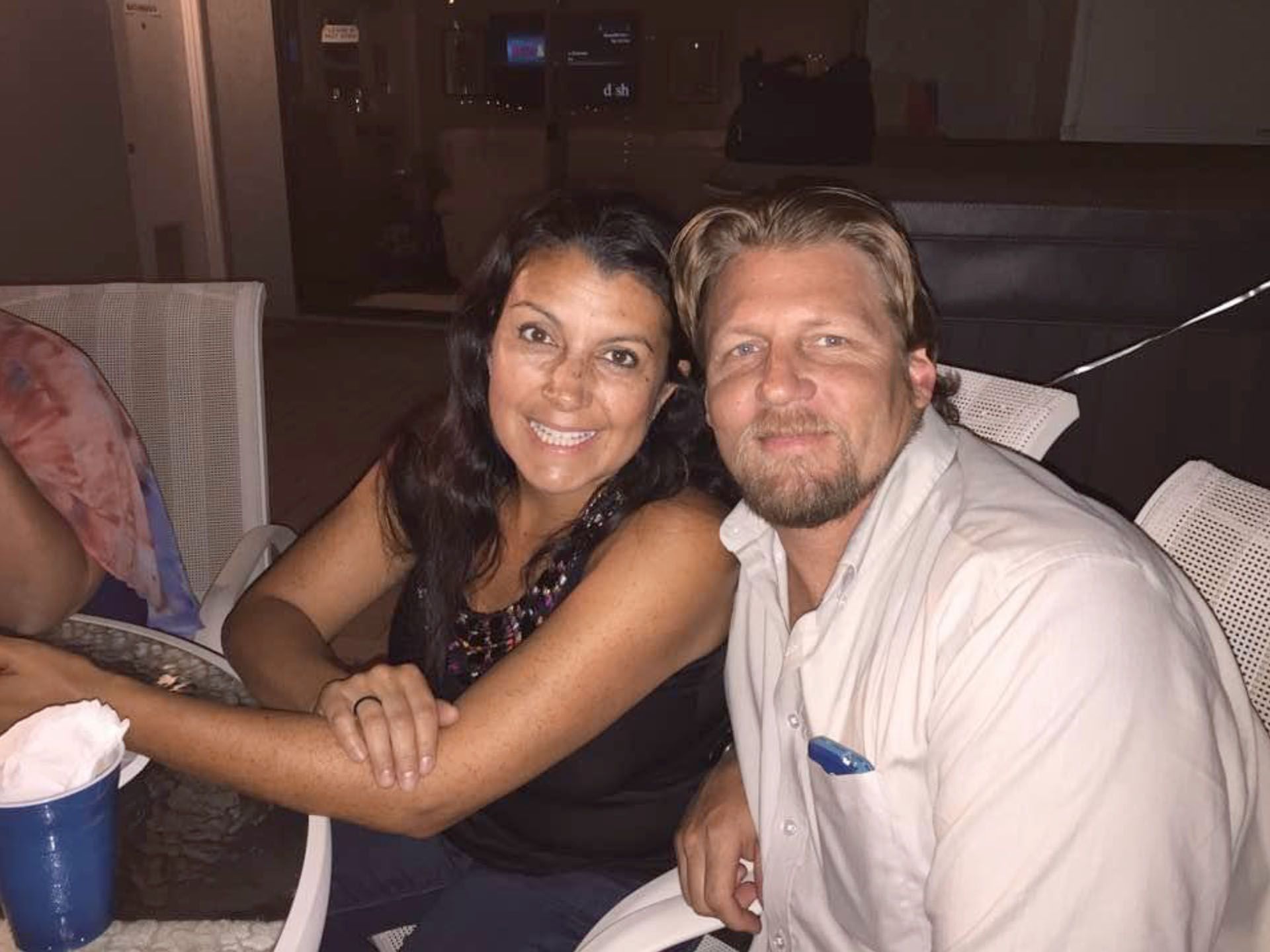 A man and a woman smiling, seated outdoors at night