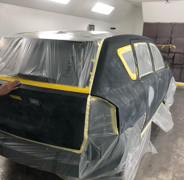 A black car is covered in plastic and tape