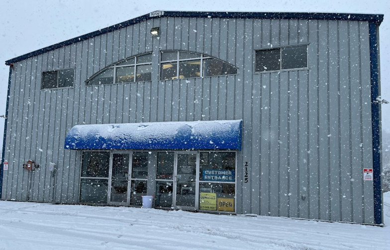 A large building with a blue awning is covered in snow.