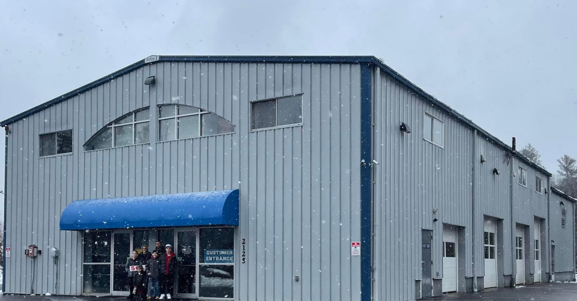 A group of people are standing in front of a large building with a blue awning.