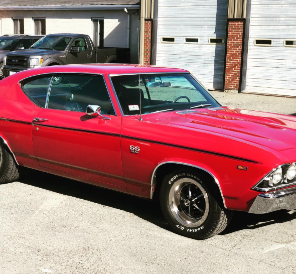 A red car is parked in front of a garage door